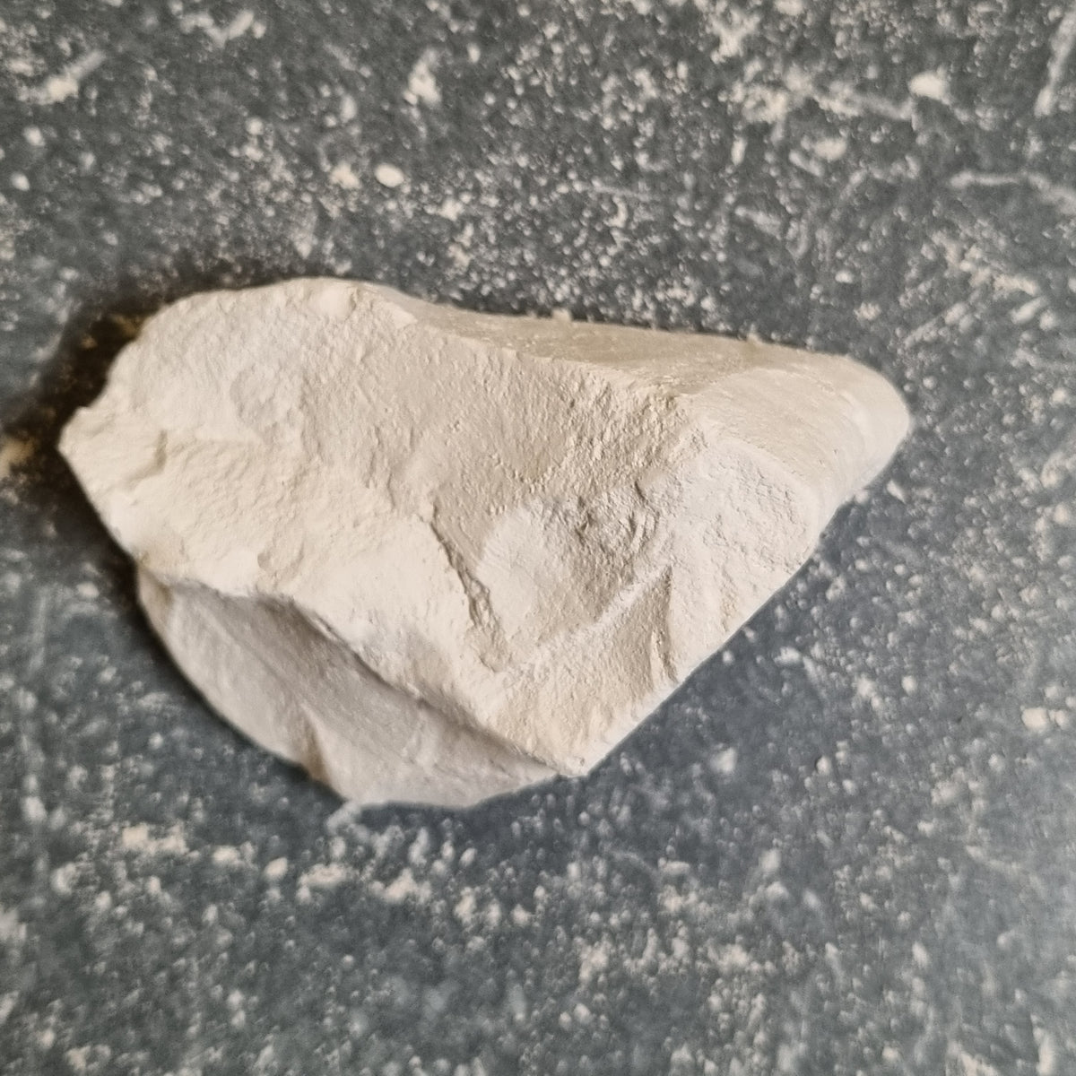 Single piece of Premium natural white chalk with a rough surface on a dark background.