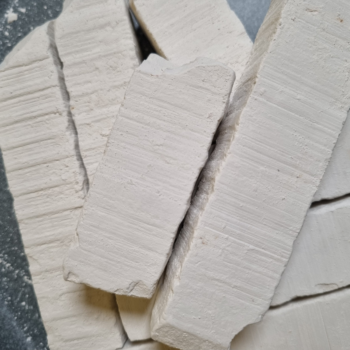 Long pieces of Vatutin natural white chalk overlapping on a dark background, showing ridged surfaces.
