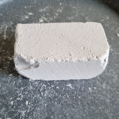 Single white Dobryj chalk block with a powdery surface on a dark tray