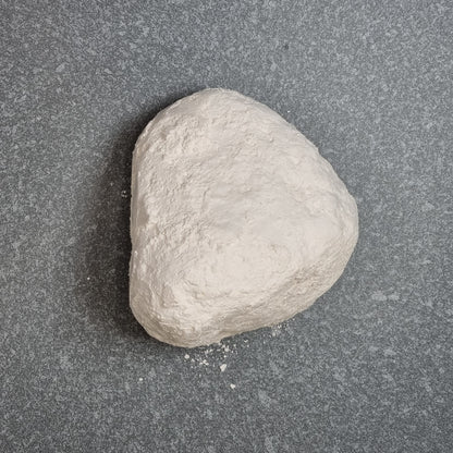 Single white Halva chalk piece with a rounded triangular shape on a dark surface