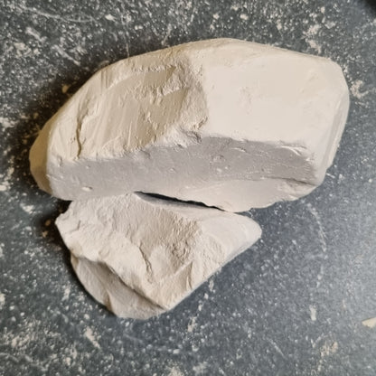 Two pieces of Premium natural white chalk with visible fracture surfaces on a dark background.