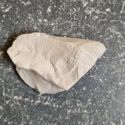 Single piece of Premium natural white chalk with a rough surface on a dark background.