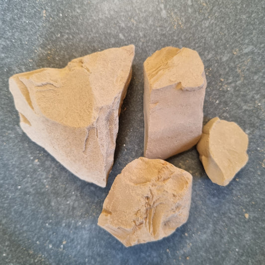 Four beige Turkestan Slivki clay pieces of different sizes arranged on a dark surface